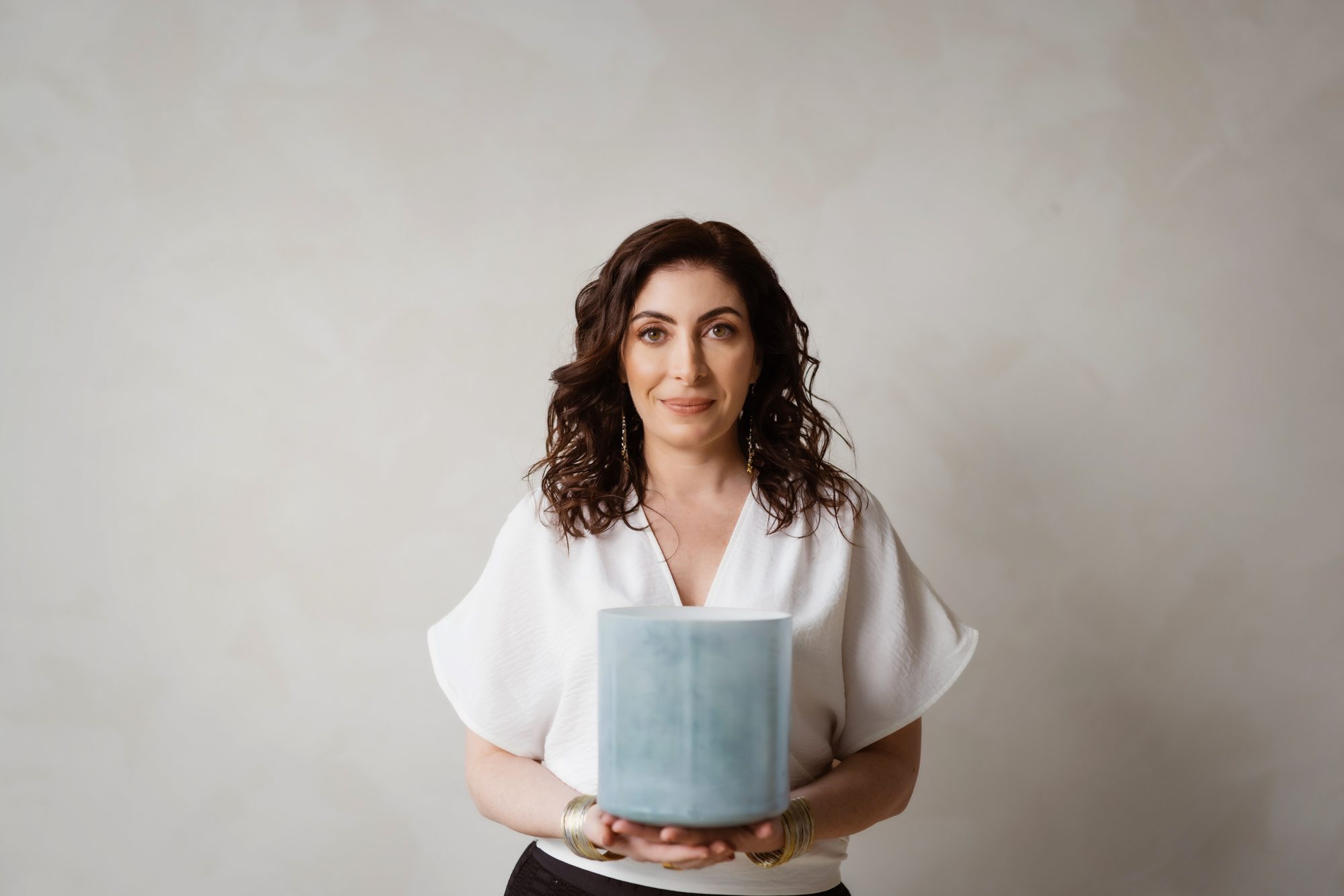 Jennifer Spencer holding a crystal singing bowl, looking directly at the camera