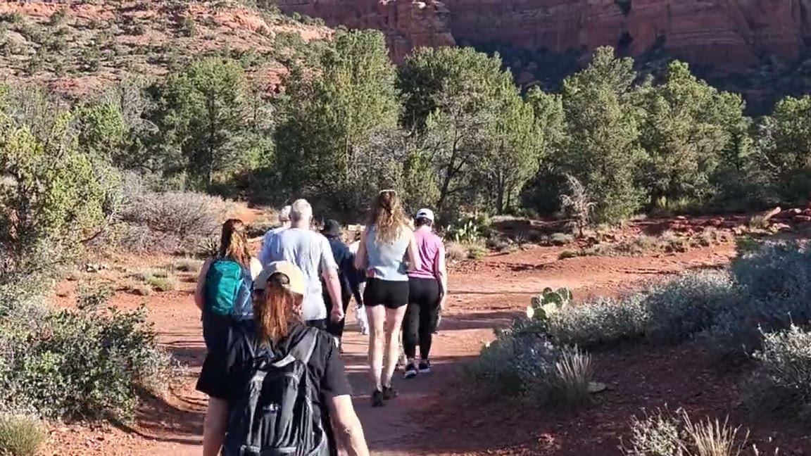 Retreat guests walking a red rock trail in Sedona together